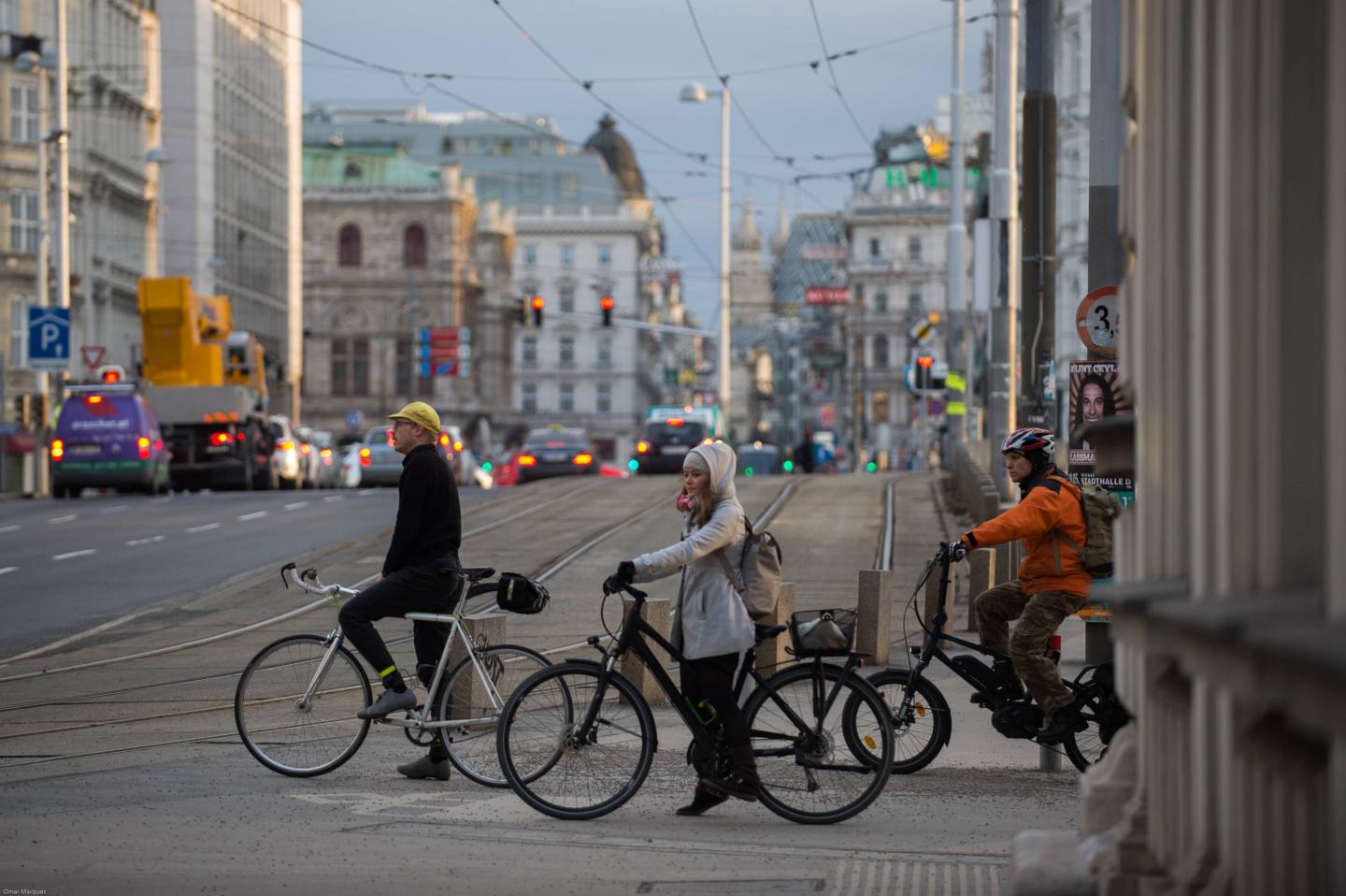 People seen on bicycles as they wait to cross the road in