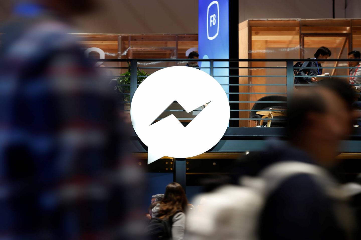 Attendees walk past a Facebook Messenger logo during Facebook Inc's annual F8 developers conference in San Jose, California