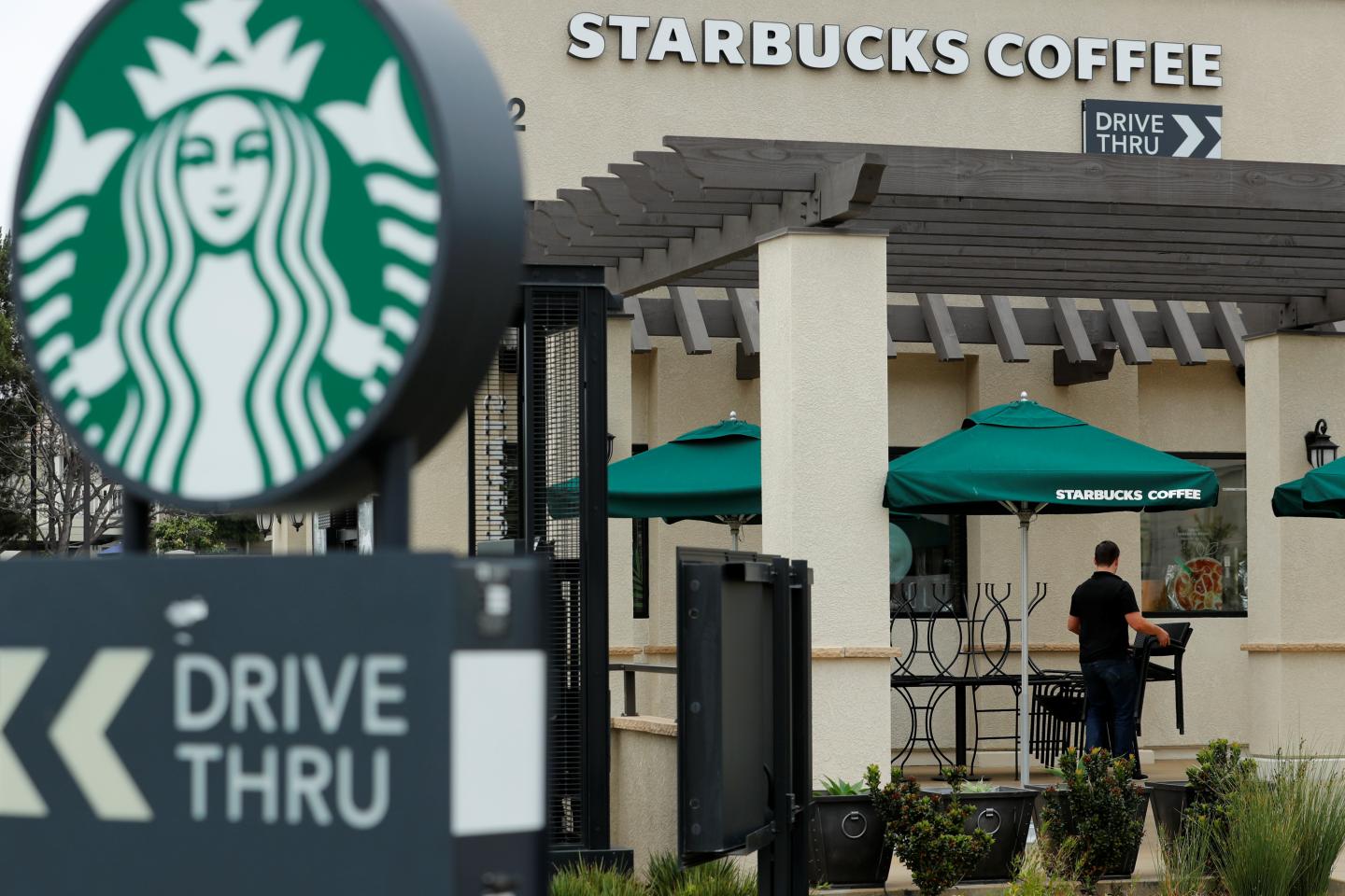 A worker puts away patio furniture at a Starbucks Corp drive-through location closes down this afternoon for anti-bias training as the coffee chain closed all 8,000 of their company-owned cafes in the U.S. including this location in Oceanside, California
