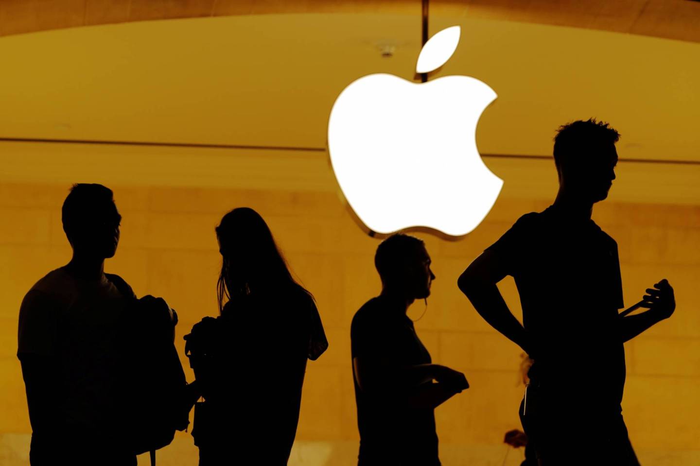Customers walk past an Apple logo inside of an Apple store at Grand Central Station in New York