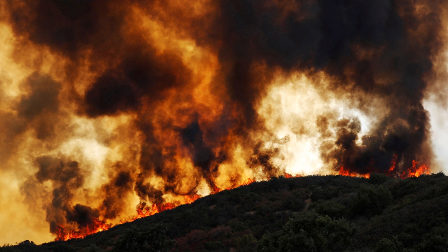 Wind-driven flames roll over a hill towards homes during the River Fire in Lakeport, California