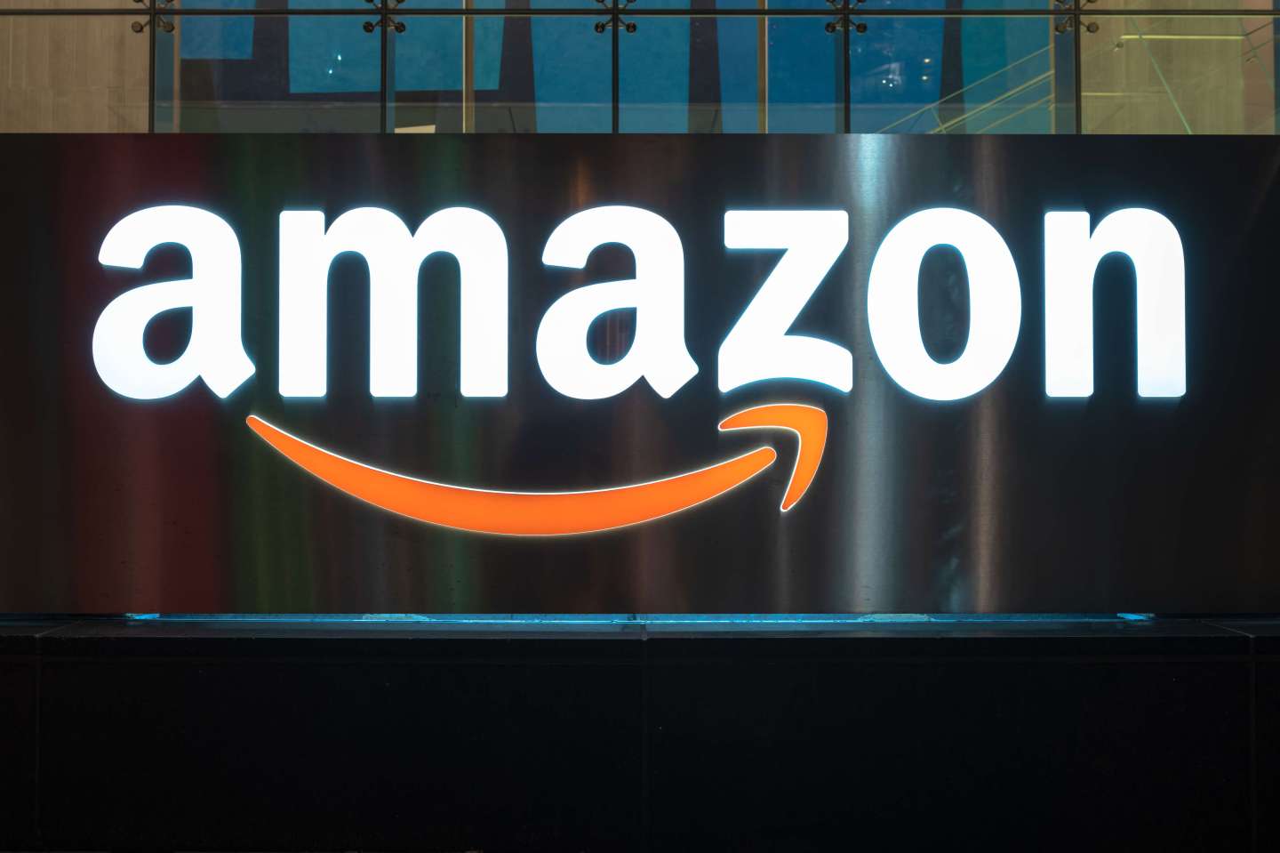 The Amazon logo illuminated at night.  The sign can be seen