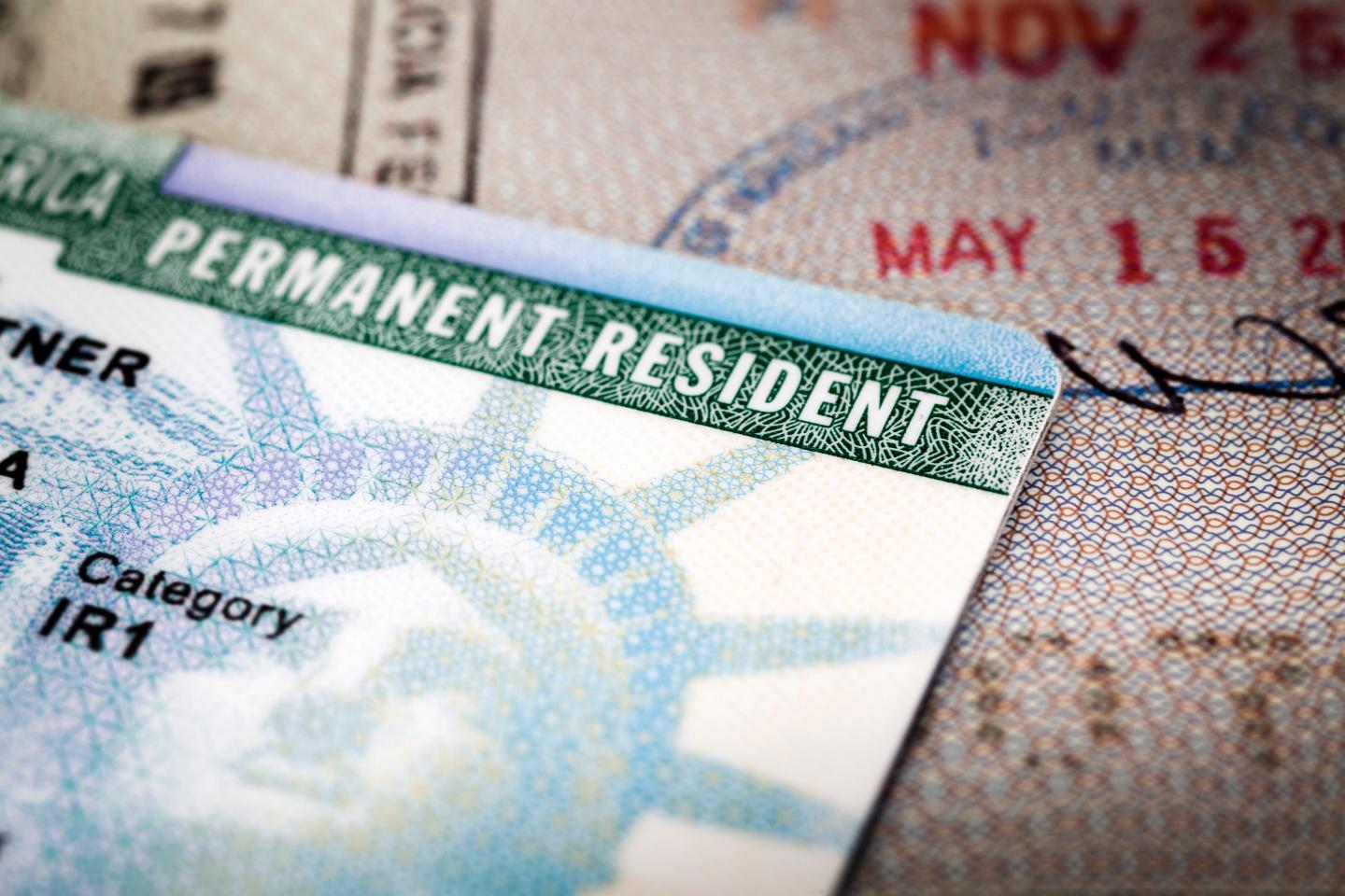 A green card lying on top of a passport