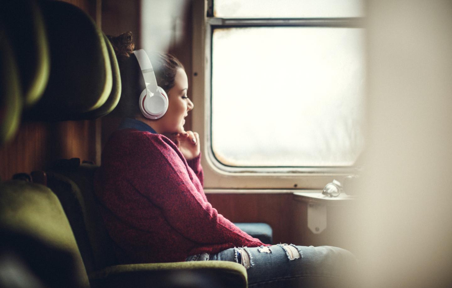 Smiling woman listening to music on smart phone in subway