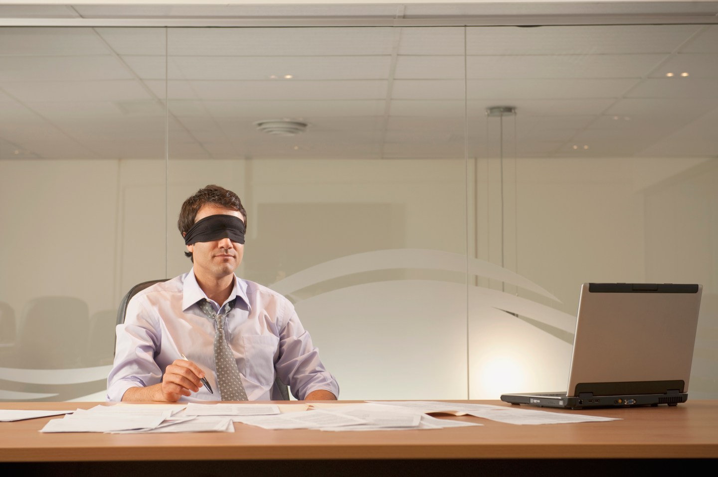 Businessman wearing a blindfold at his desk