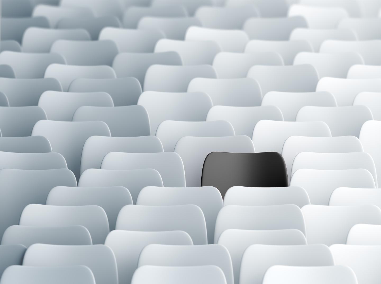 Black chair in a lecture hall full of white ones. Individuality, discrimination and contrasts concept