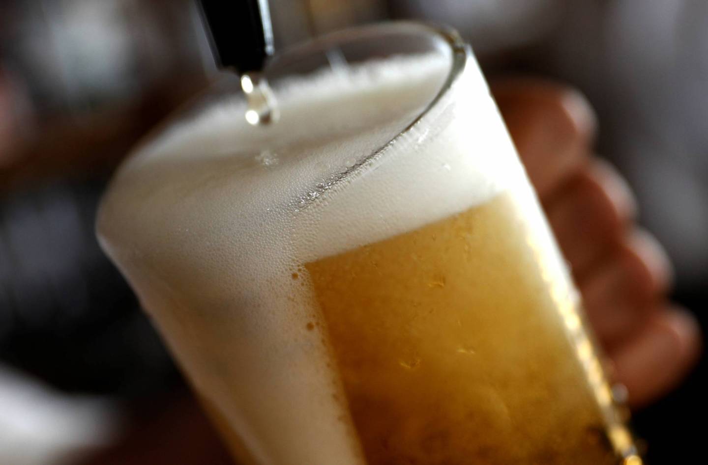 A pint of beer is poured into a glass in a bar in London