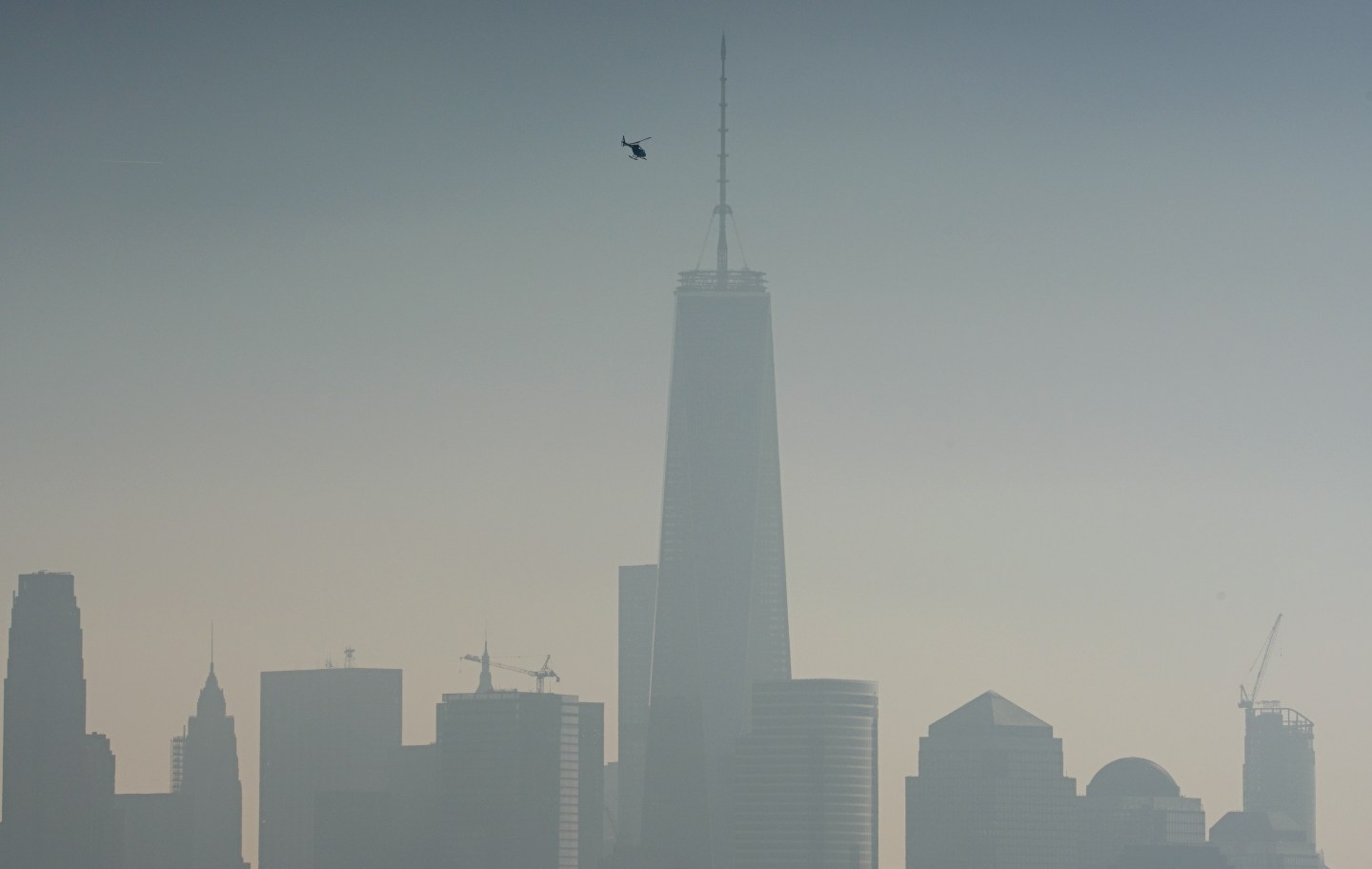 A helicopter flies over the Hudson River with One World Trade Center in the background in New York City