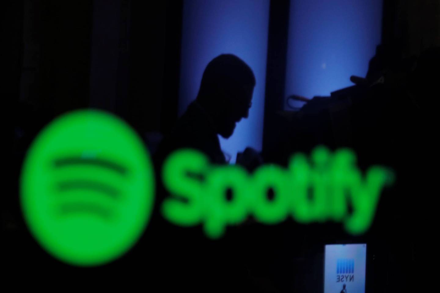 A trader is reflected in a computer screen displaying the Spotify brand before the company begins selling as a direct listing on the floor of the New York Stock Exchange in New York