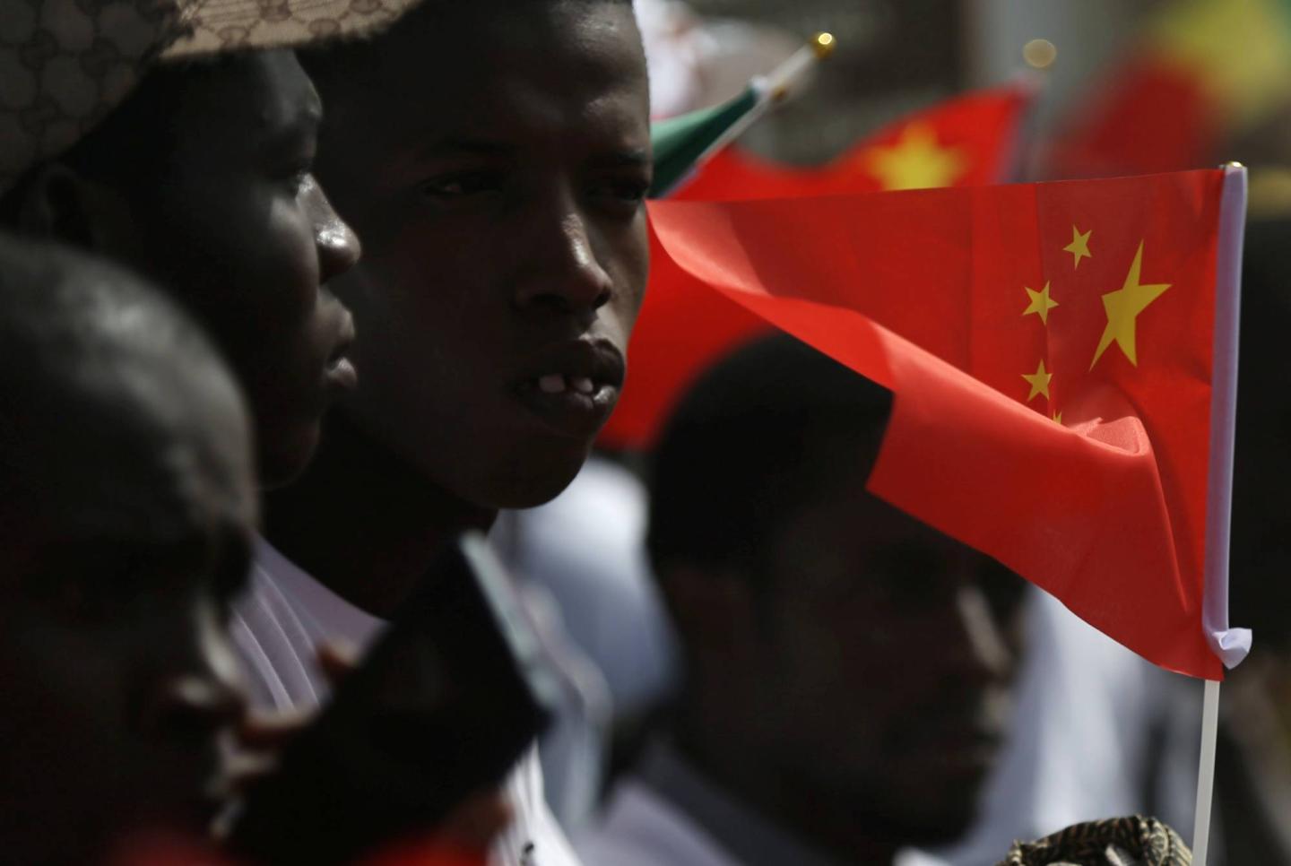 Well wishers holding flags wait for the arrival of Chinese President Xi Jinping at the Leopold Sedar Senghor International Airport at the start of his visit to Dakar