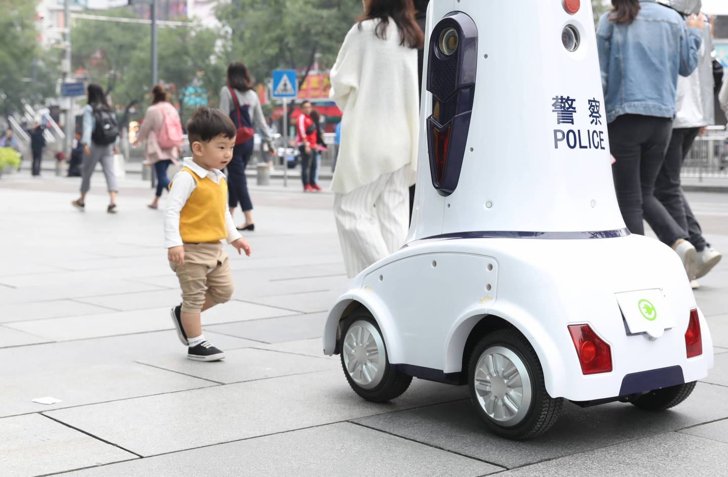 A child follows a police robot on duty in Xidan commercial district on Sept. 27, 2018, in Beijing, China.