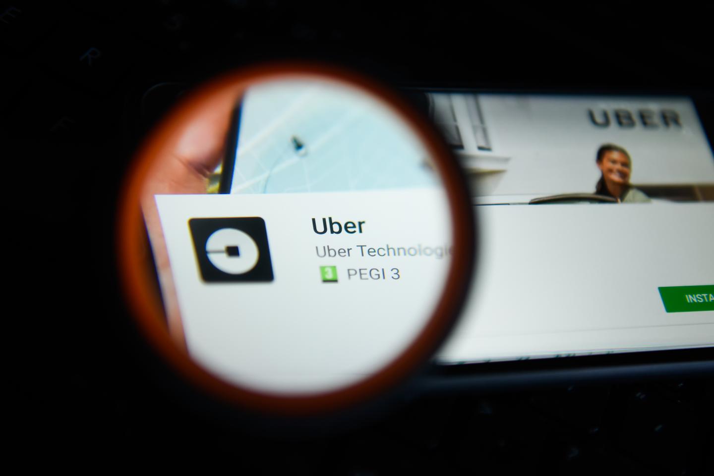 Uber logo  is seen trough a magnifying glass on an android