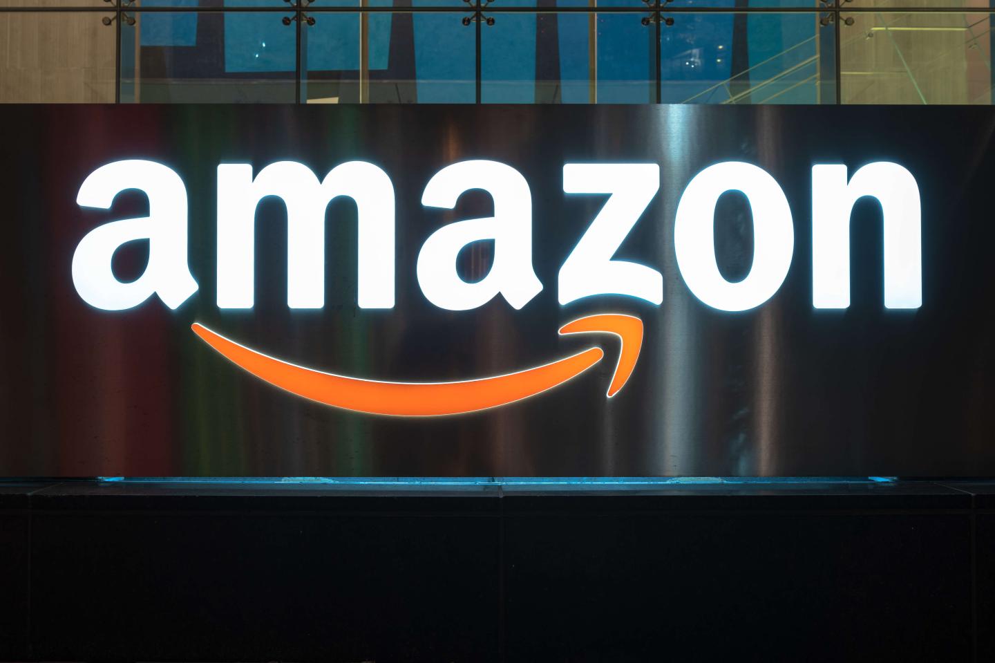 The Amazon logo illuminated at night. The sign can be seen