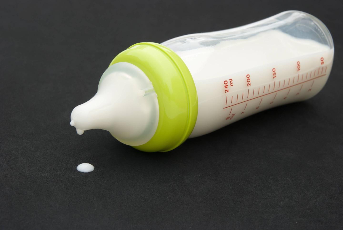 baby bottle with milk on black background