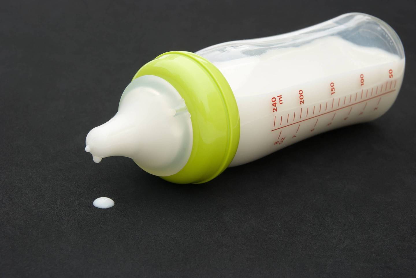 baby bottle with milk on black background