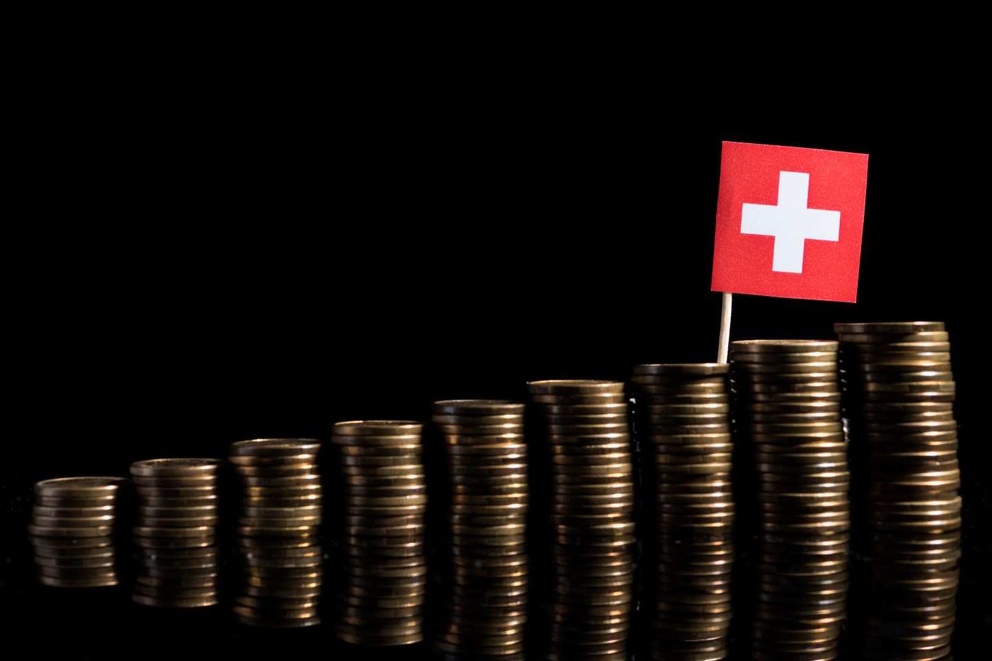Swiss flag with lot of coins isolated on black background