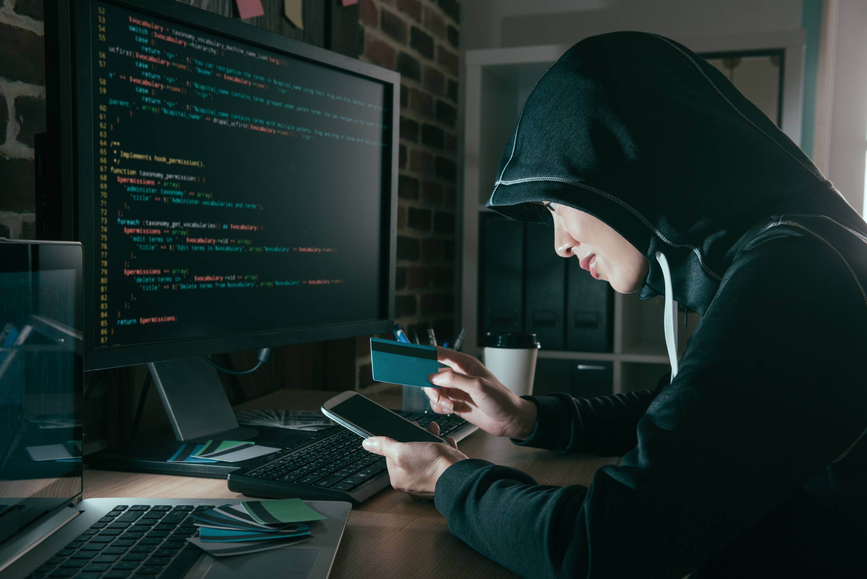 hacker holding credit card and mobile smartphone