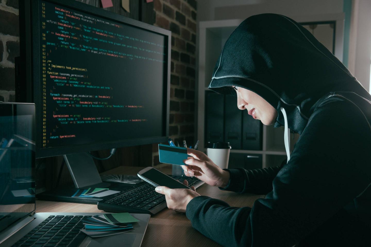 hacker holding credit card and mobile smartphone