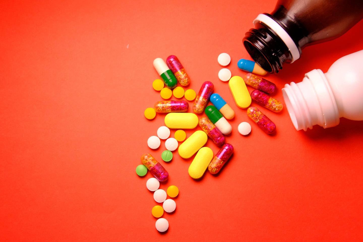 colourful pills spilled on red background.