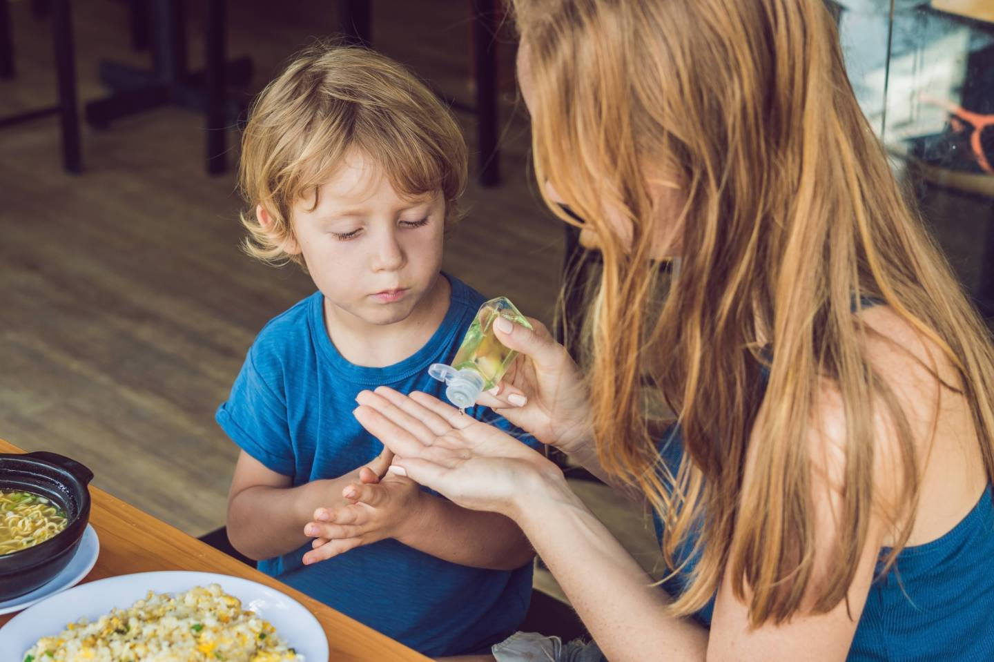 Mother and son using wash hand sanitizer gel in the cafe