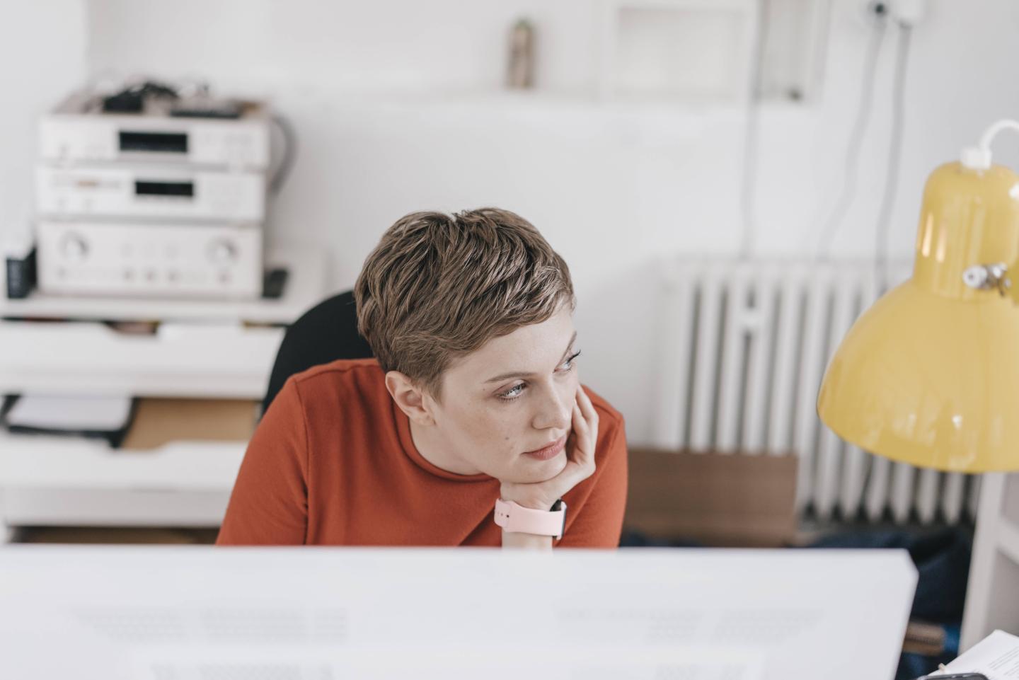 A woman is thinking at her desk.
