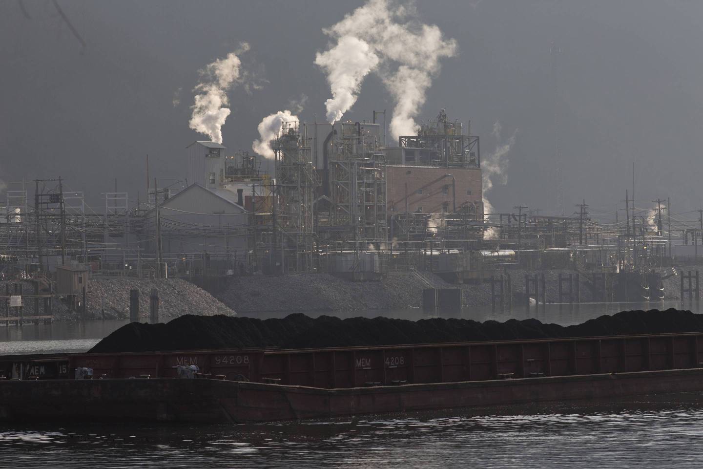 A coal barge travels up the Kanawha River, passing the DuPont chemical plant, just south of Charleston, W.Va.