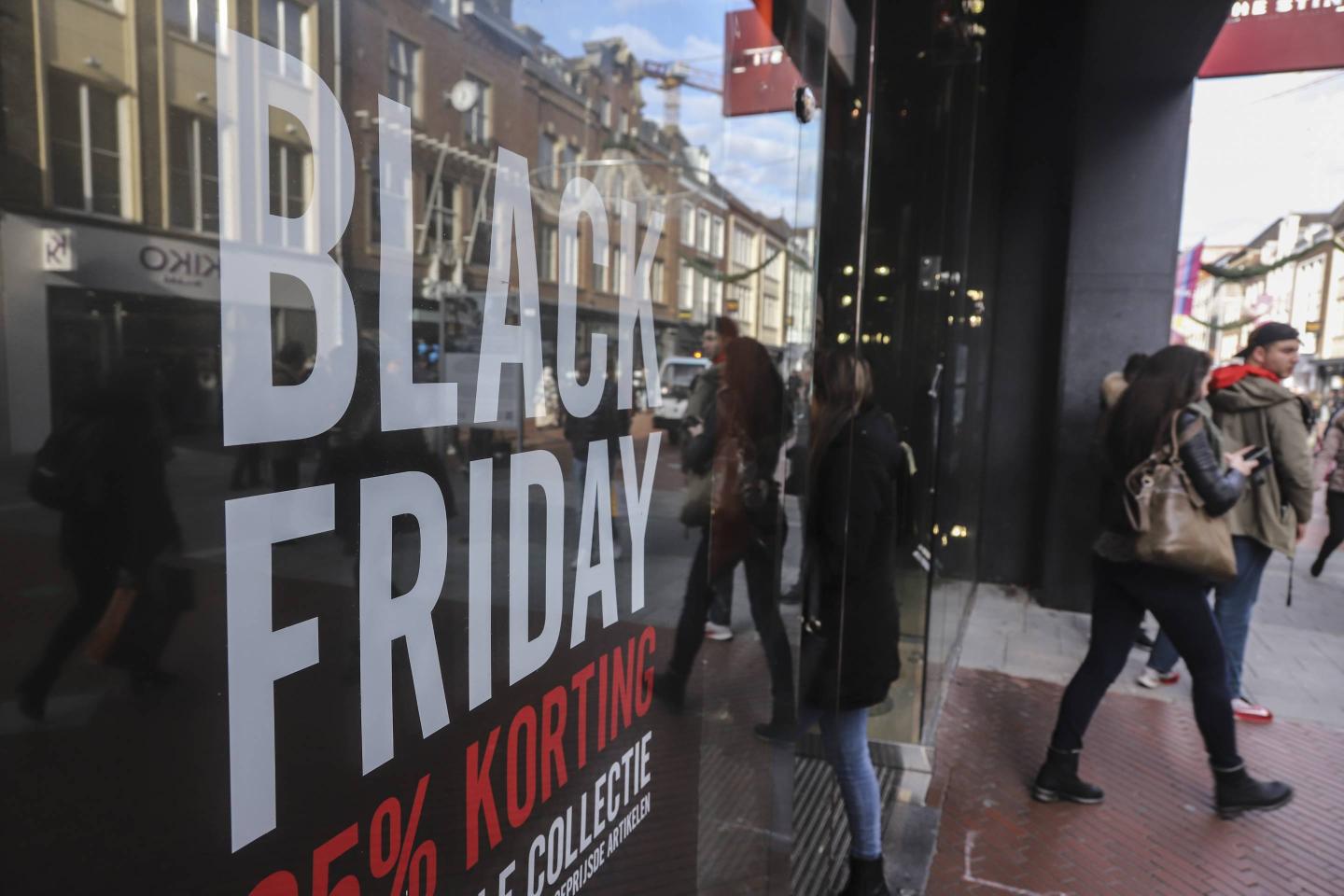 People seen walking by a Black Friday signs with discounts