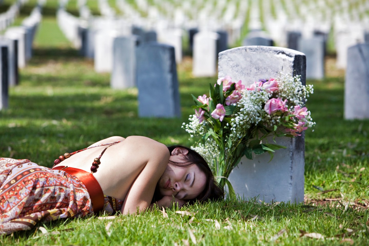 Mourning woman lying down by grave marker