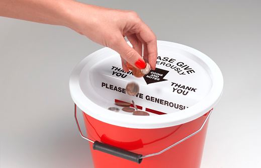 Coins being donated in charity bucket