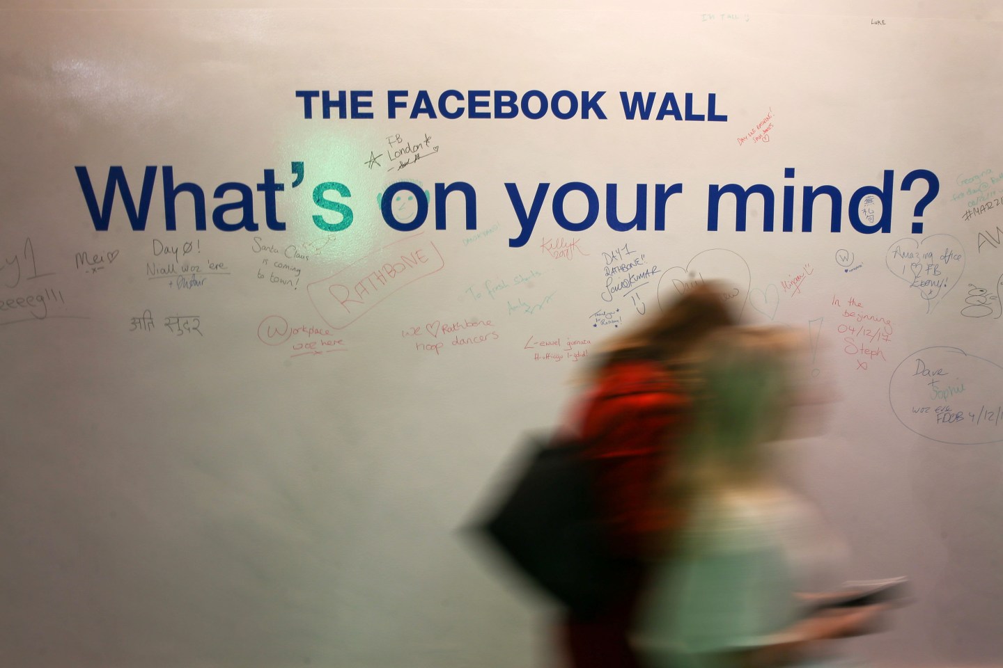 Employees walk past the Facebook Wall at Facebook's new headquarters, designed by Canadian-born American architect Frank Gehry, at Rathbone Place in central London on December 4, 2017