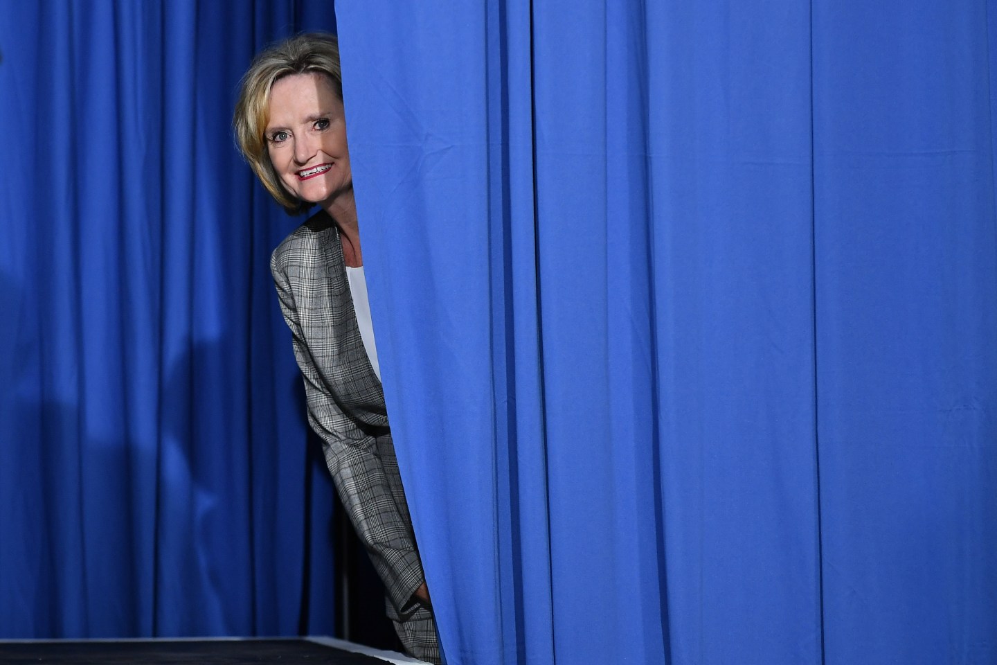 Senator Cindy Hyde-Smith peaks out from behind a curtain before a rally with US President Donald Trump at Landers Center Ð Arena in Southaven, Mississippi, on October 2, 2018
