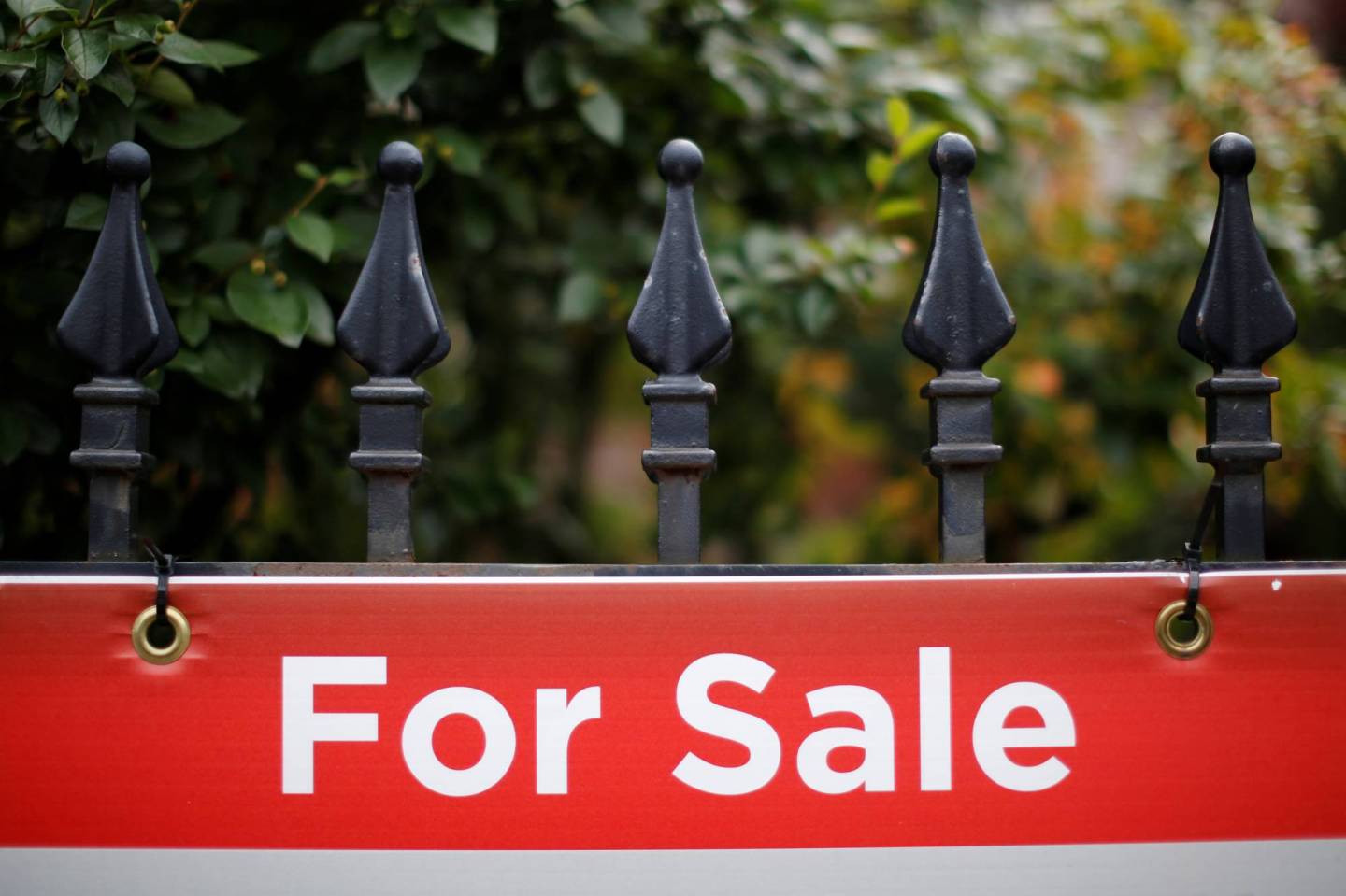 A real estate sign is seen hanging on a fence in front of a house for sale in Ottawa