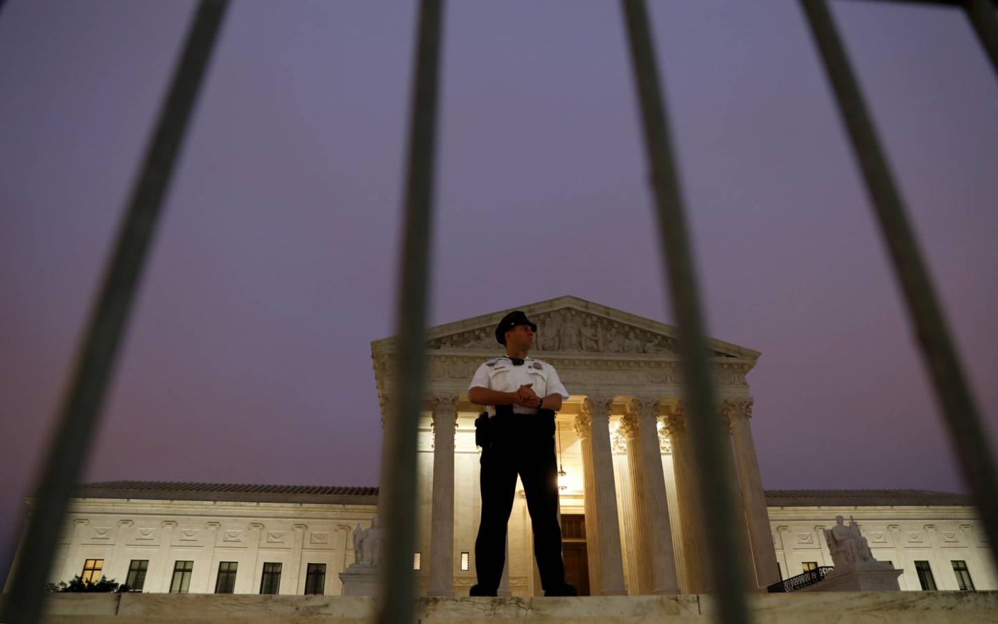 Lone U.S. Supreme Court officer guards the steps of the court after Justice Kavanaugh was sworn in as a justice inside in Washington