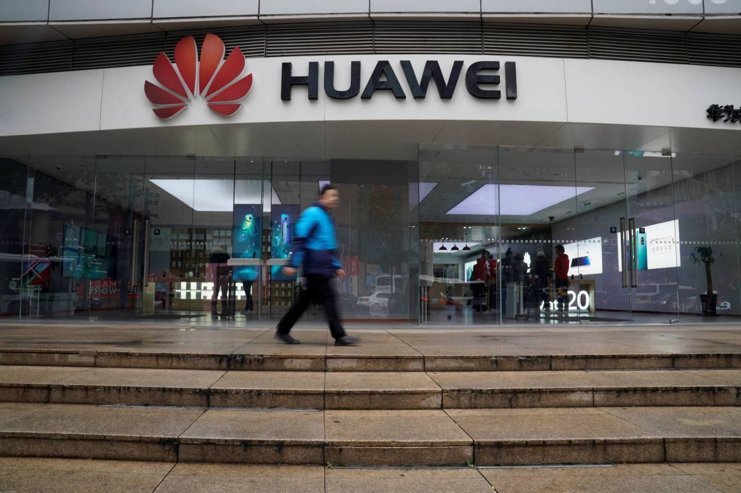 A man walks by a Huawei logo at a shopping mall in Shanghai
