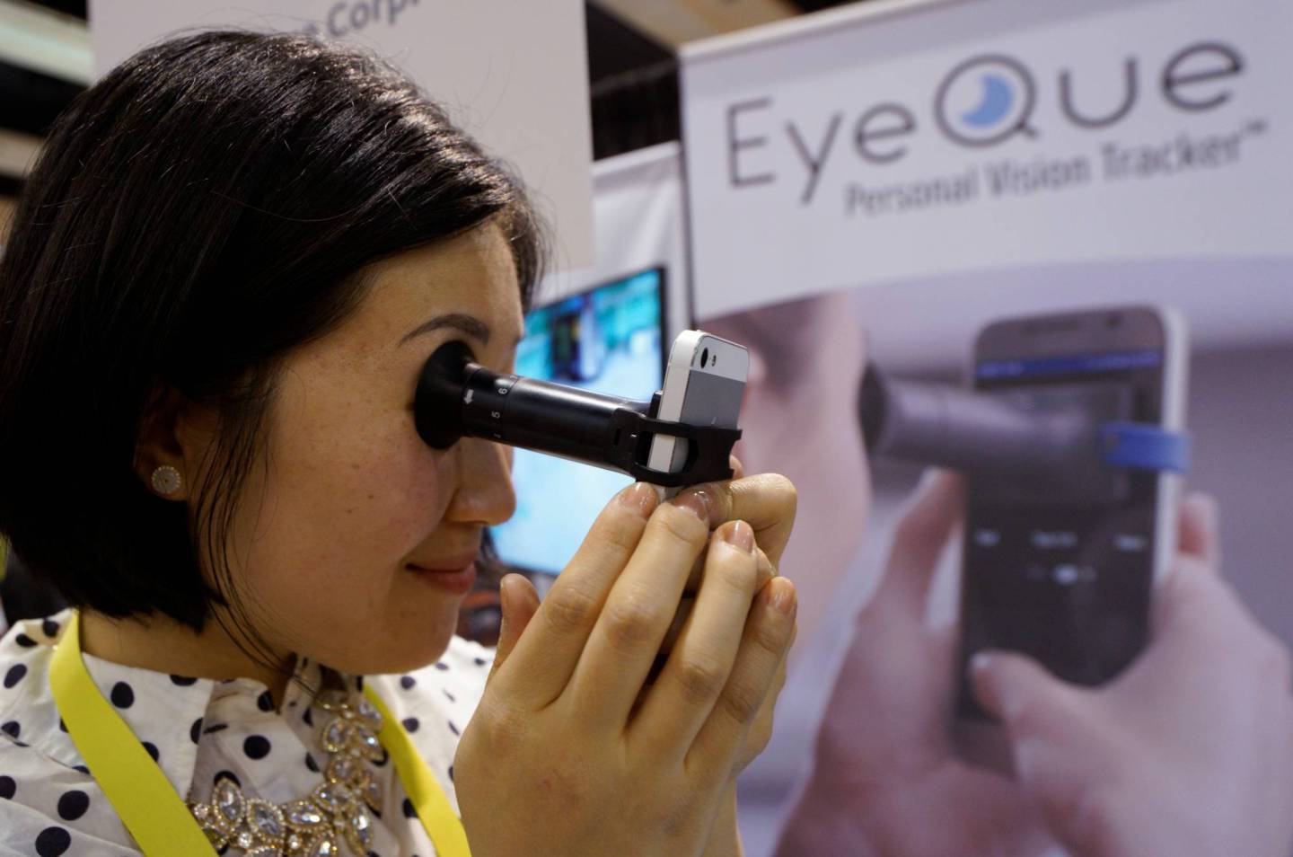 Phoebe Yu of Eyeque Corp., demonstrates her EyeQue vision testing device attached to a smart phone at CES in Las Vegas