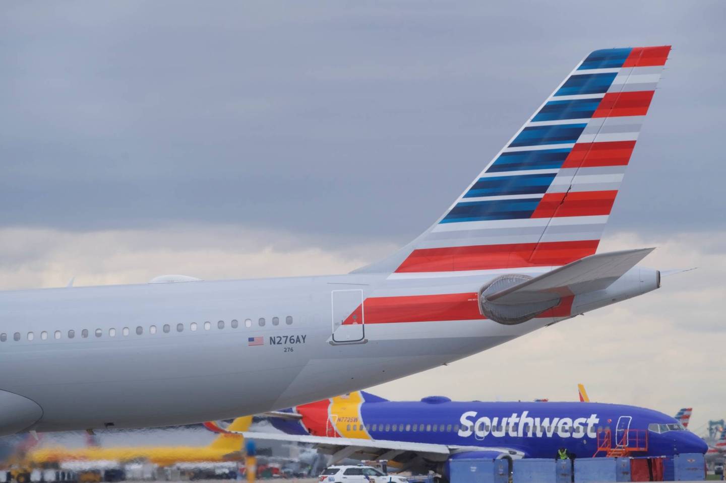 An airplane passes in front of Southwest Airlines Flight 1380, which diverted to the Philadelphia International Airport this morning after the airline crew reported damage to one of the aircraft's engines, on a runway in Philadelphia, Pennsylvania