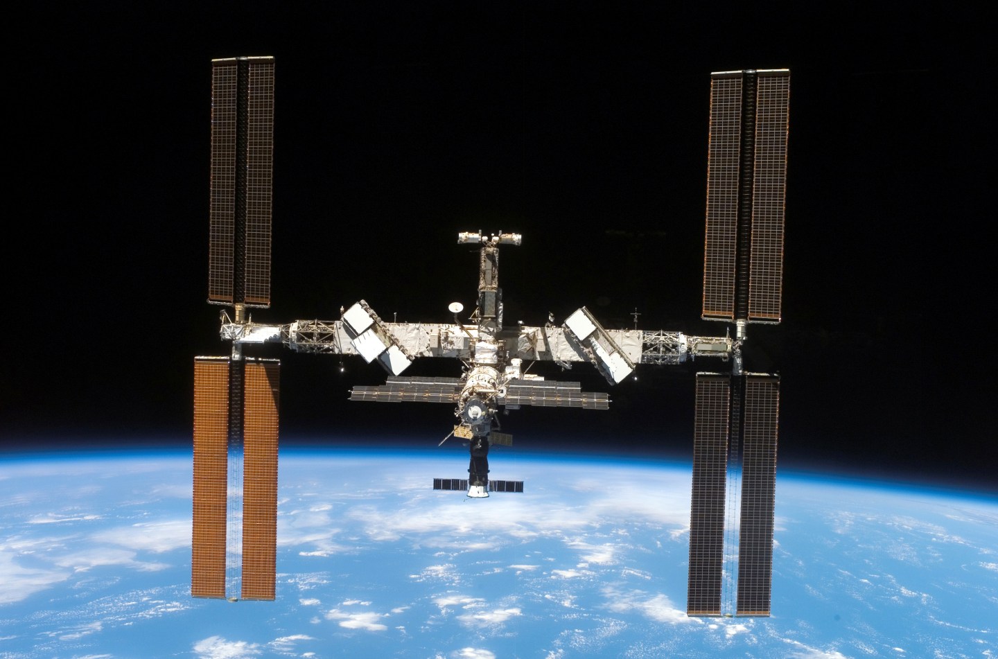 Backdropped by the blackness of space and Earths horizon, the International Space Station and Space Shuttle Atlantis move farther apart at the end of STS-117s mission, during which the shuttle and station crews concluded about eight days of cooperative wor