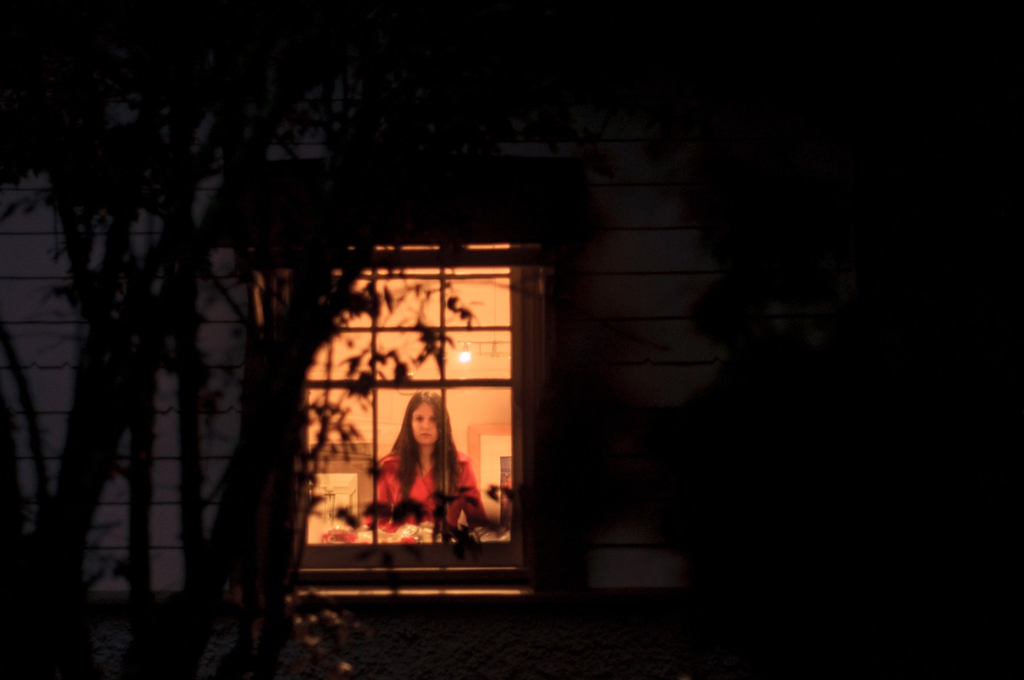 Young woman standing behind window, front view