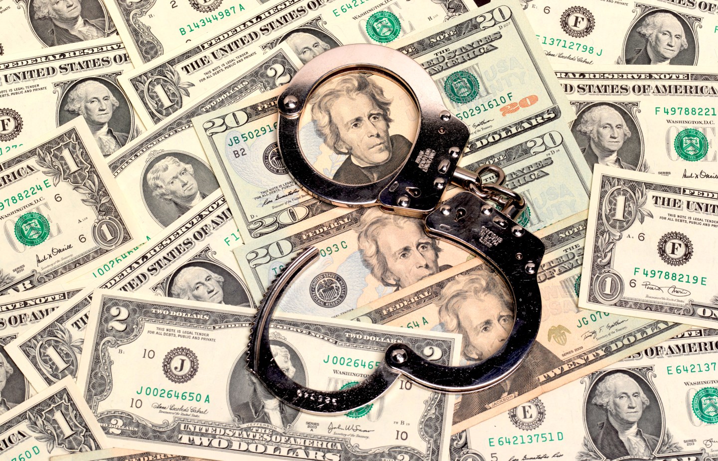handcuffs sitting on top of US paper currency