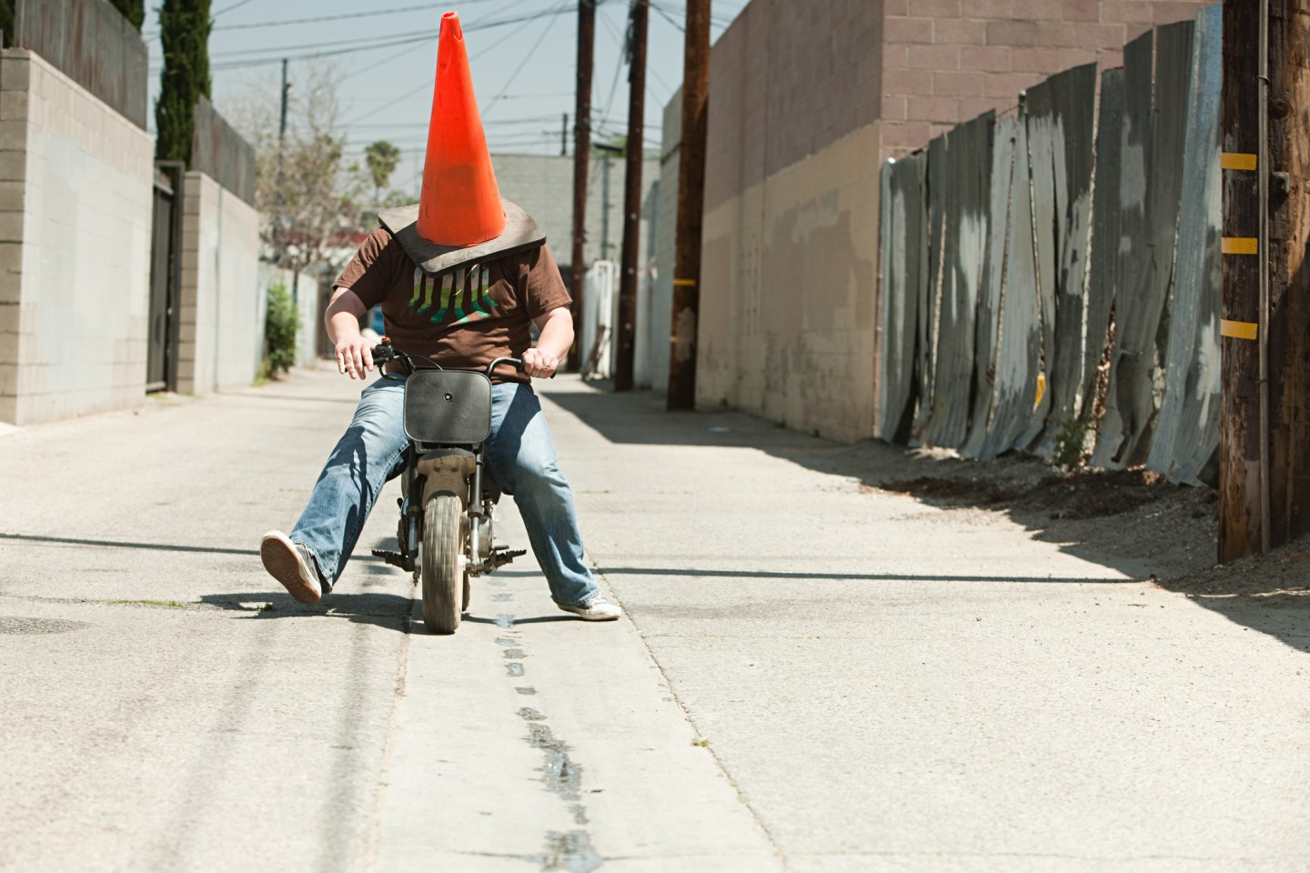 Man with traffic cone on head, riding motorbike