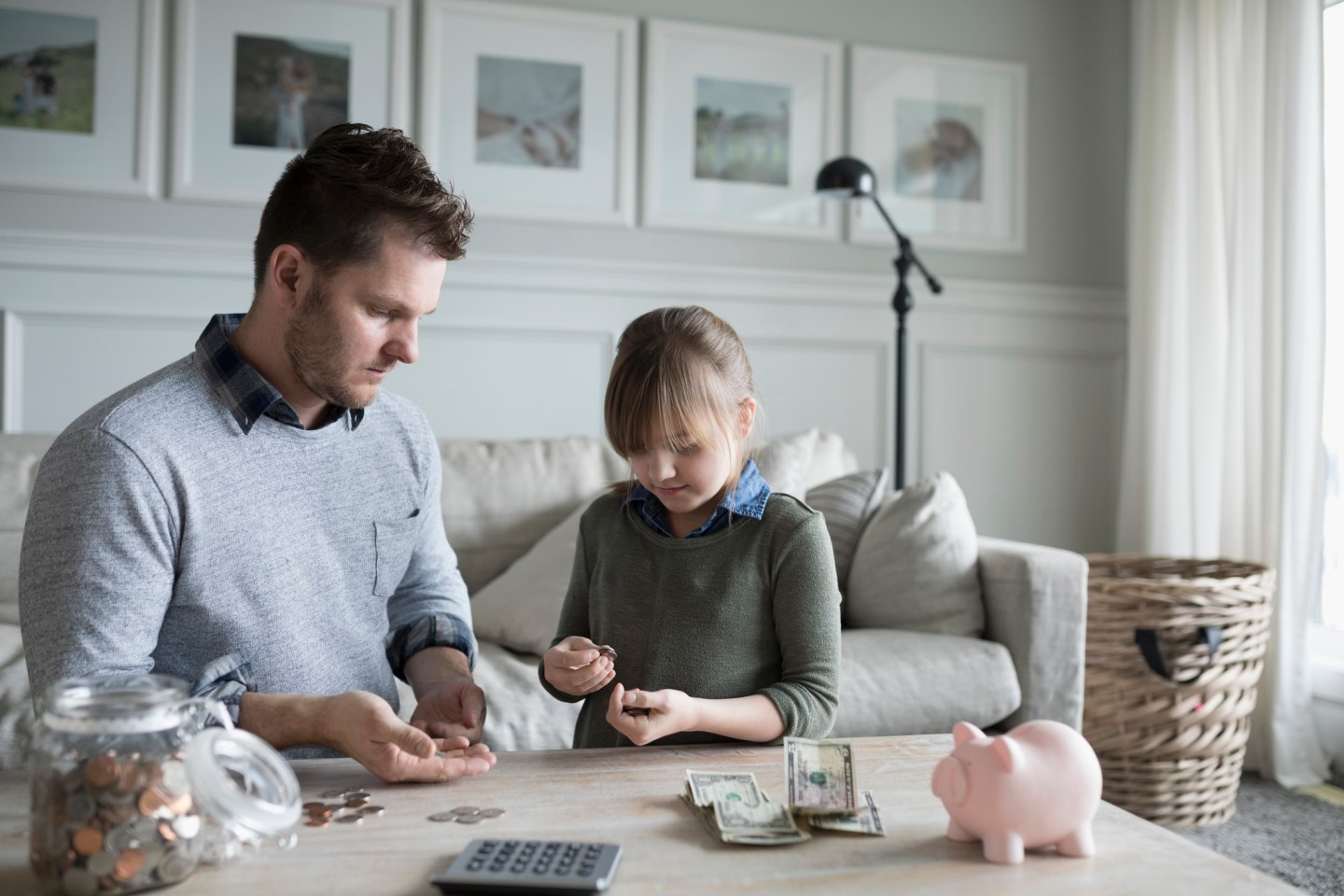 Father teaching daughter counting allowance money in living room