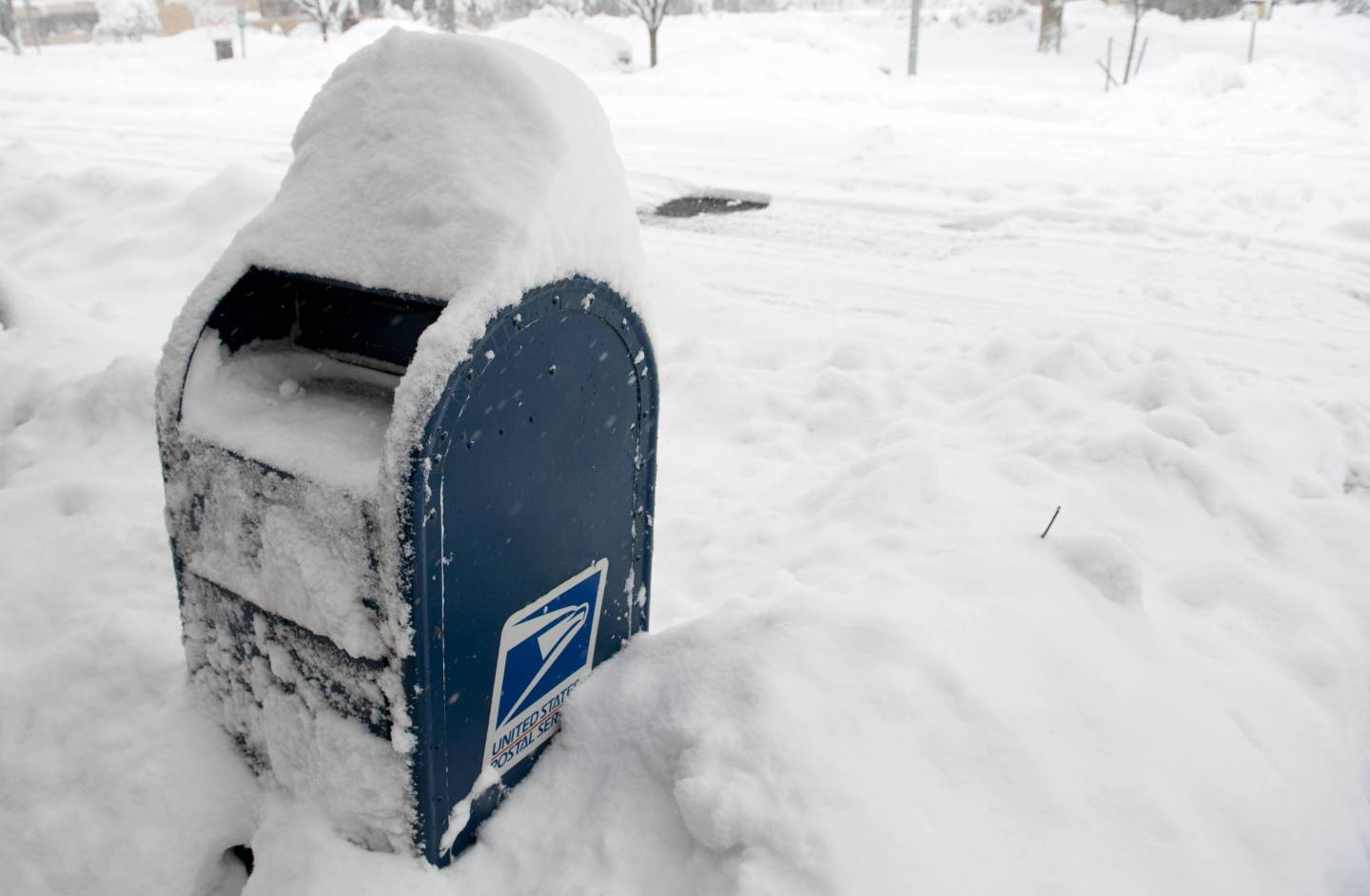 Snow blankets a USPS mailbox during a sn