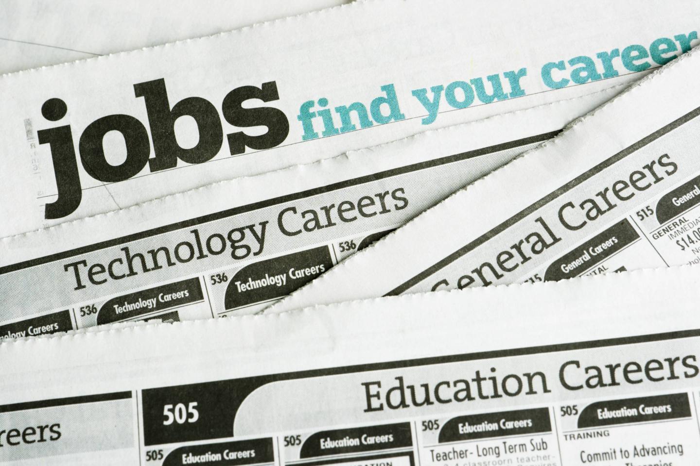 Newspaper job listing pages are stacked to illustrate the job search and the job hunting process.