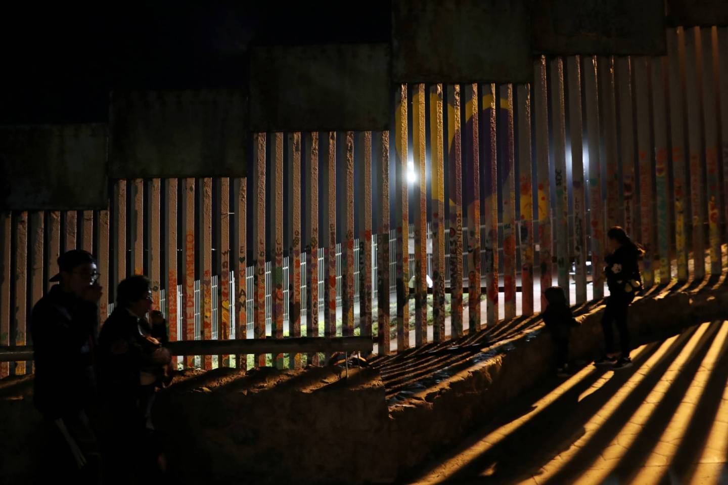 People in silhouette are seen in front of the U.S. and Mexico border fence at Friendship Park in Tijuana, Mexico