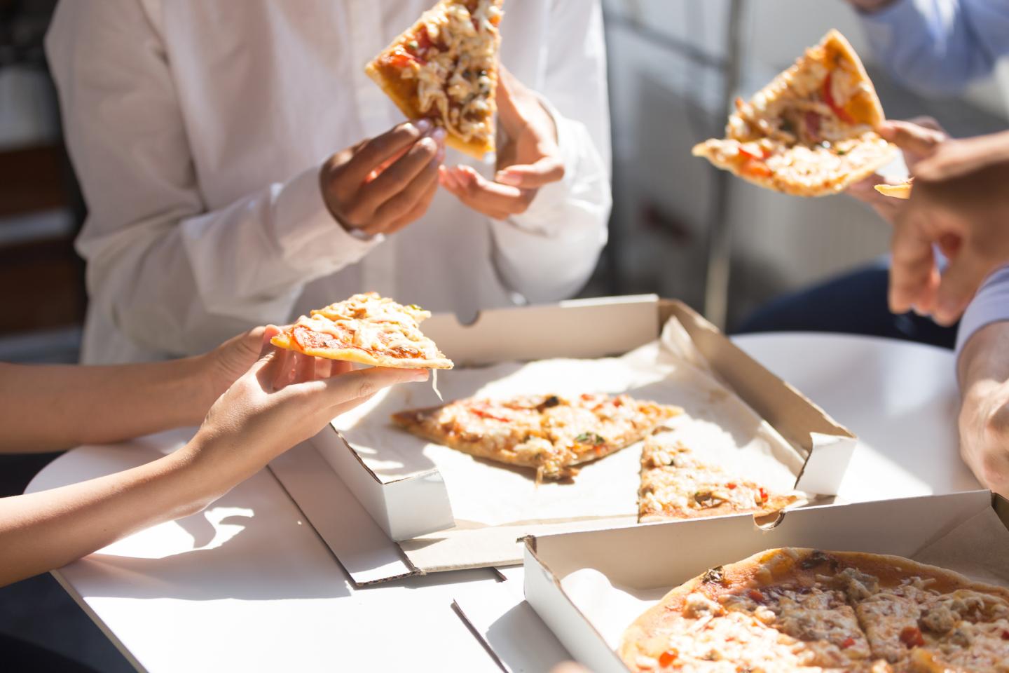 Close up business people eating pizza during lunch