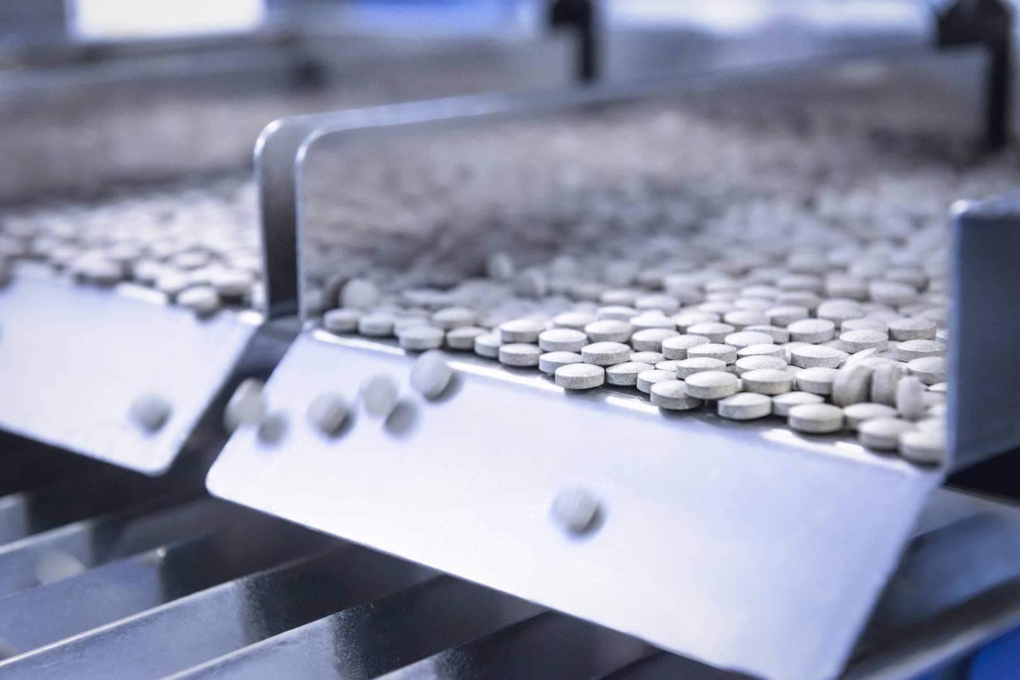 Close up of tablets in packing machine in pharmaceutical factory