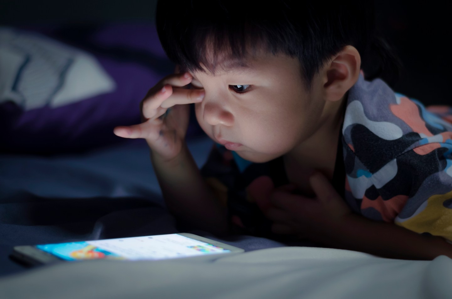 kid with tablet in the dark on bed and reading at Night .