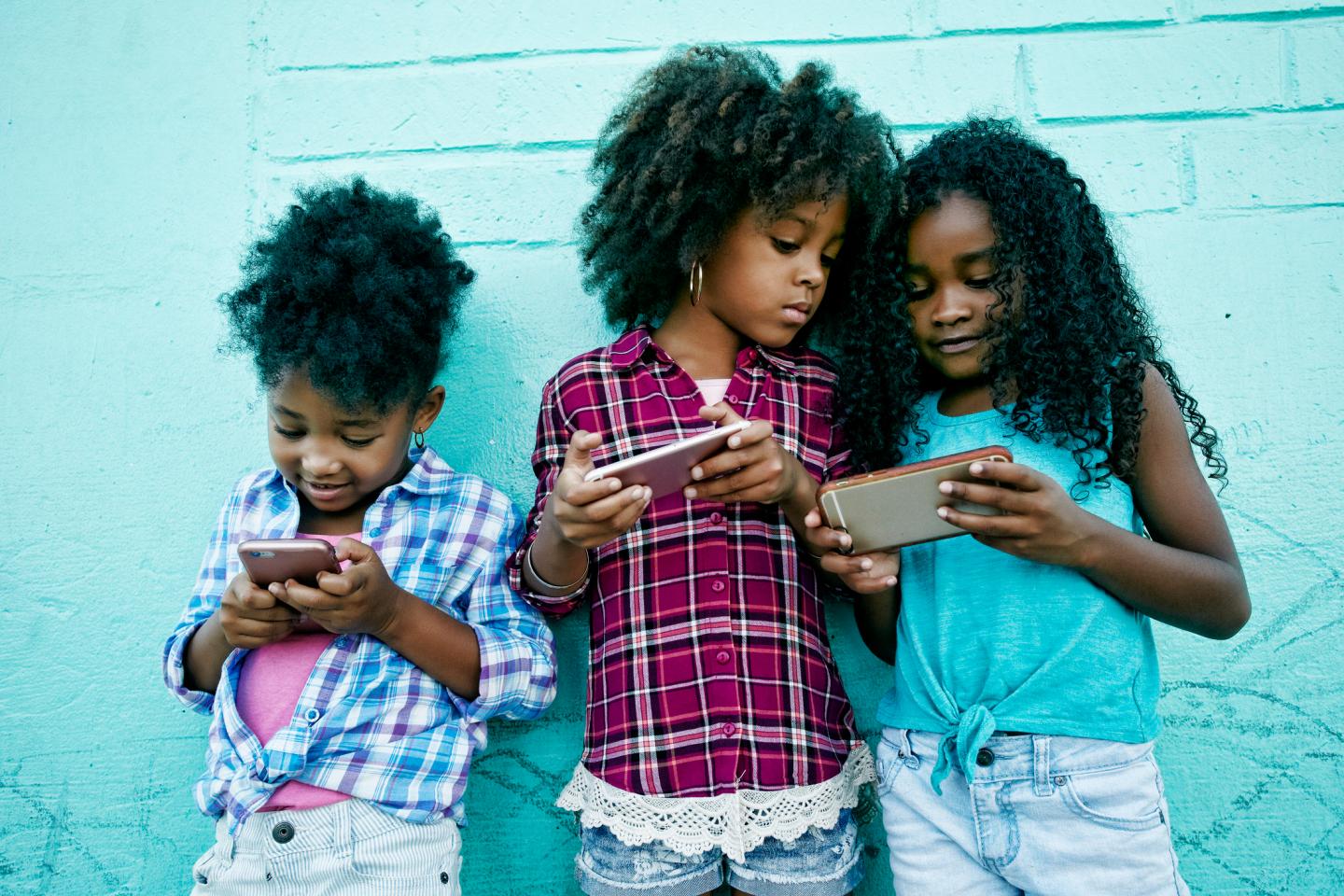 Girls leaning on wall texting on cell phones