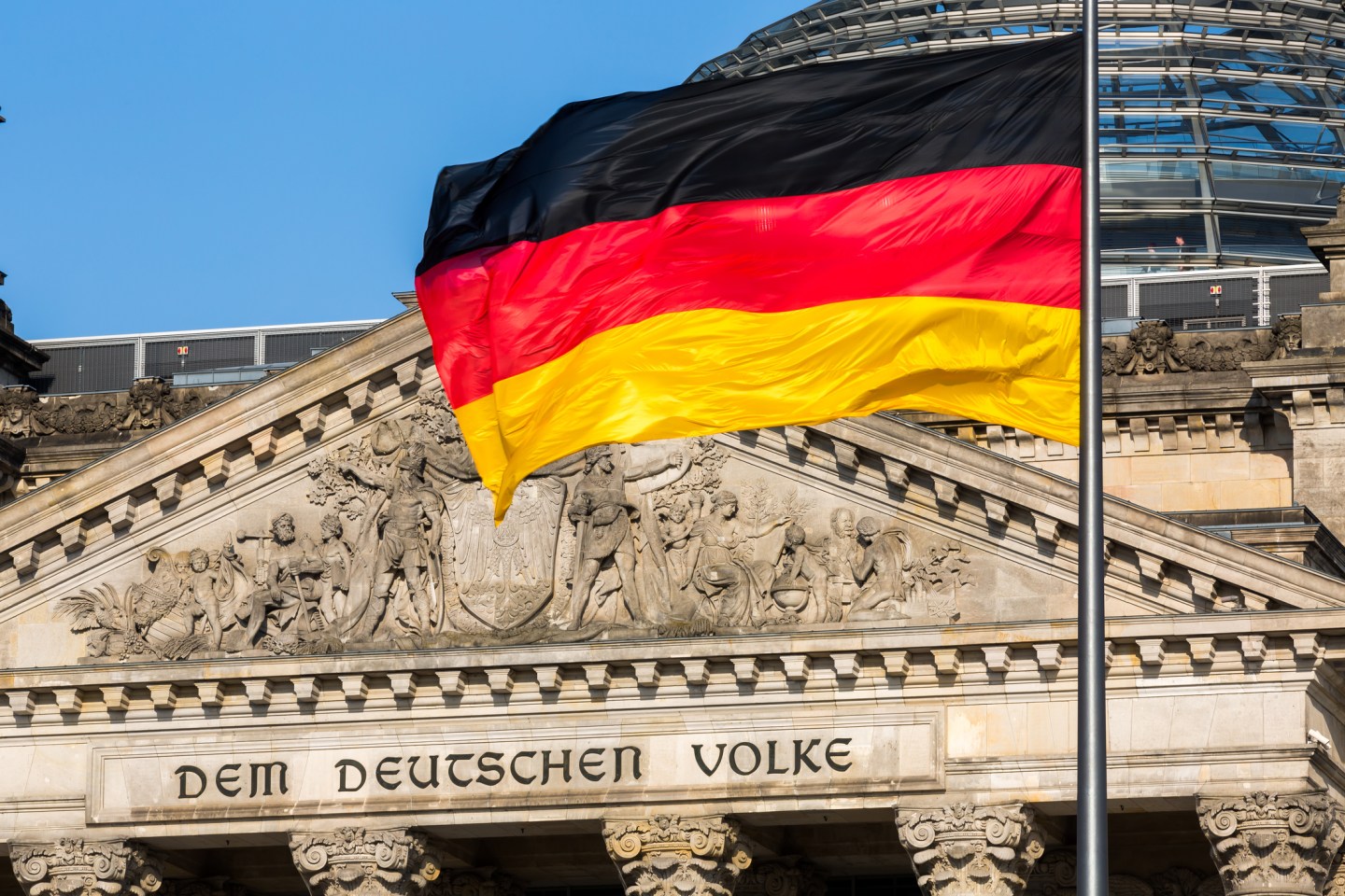 The famous inscriptionon the west portal of the Reichstag building in Berlin: "Dem Deutschen Volke" with german flag
