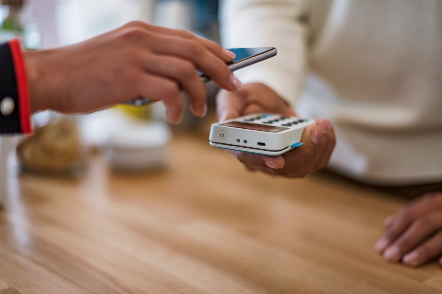 Close-up of customer paying cashless with smartphone at counter of a store